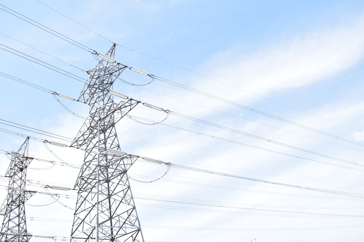 High voltage transmission towers and conductors against a blue sky